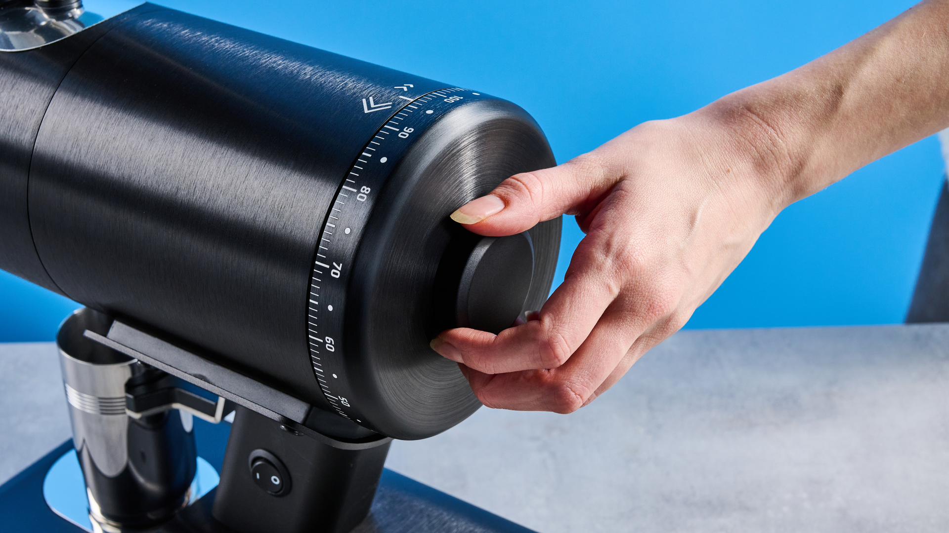 ο μύλος καφέ mazzer philos σε μαύρο και ανοξείδωτο ατσάλι φωτογραφισμένο σε μπλε φόντο με οδηγό tom