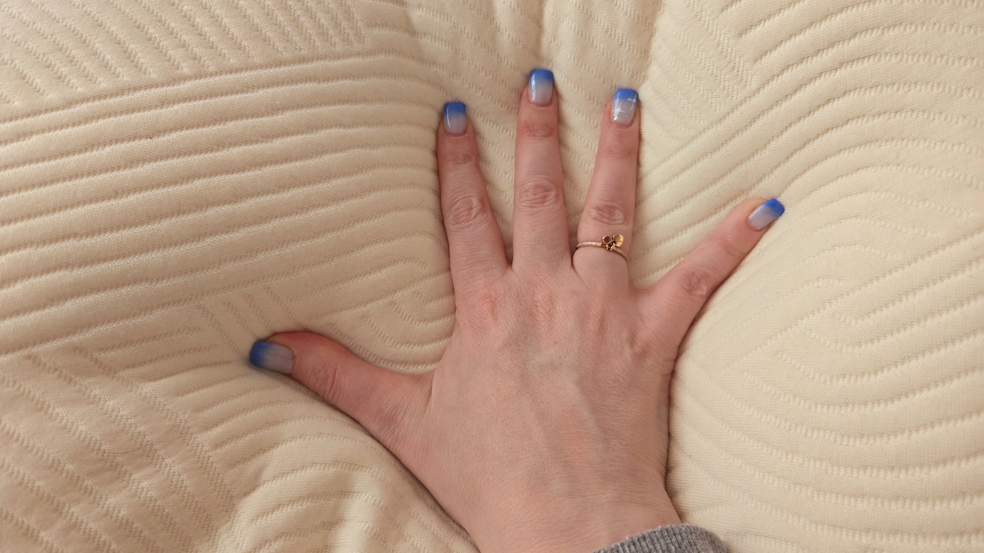 Το περιποιημένο χέρι του δοκιμαστή μας πιέζει μέσα στο ρυθμιζόμενο μαξιλάρι λάτεξ Coop Sleep Goods