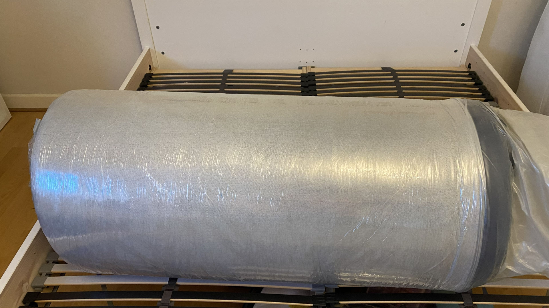 The Simba Hybrid Pro mattress on a bed frame, still rolled up in plastic