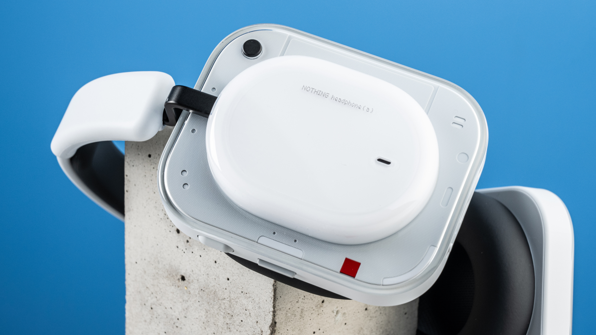 the nothing headphone (a) photographed against the blue tom's guide background, showing the transparent and white ear cups with red accents, the padded headband, and the accessories including 3.5mm jack