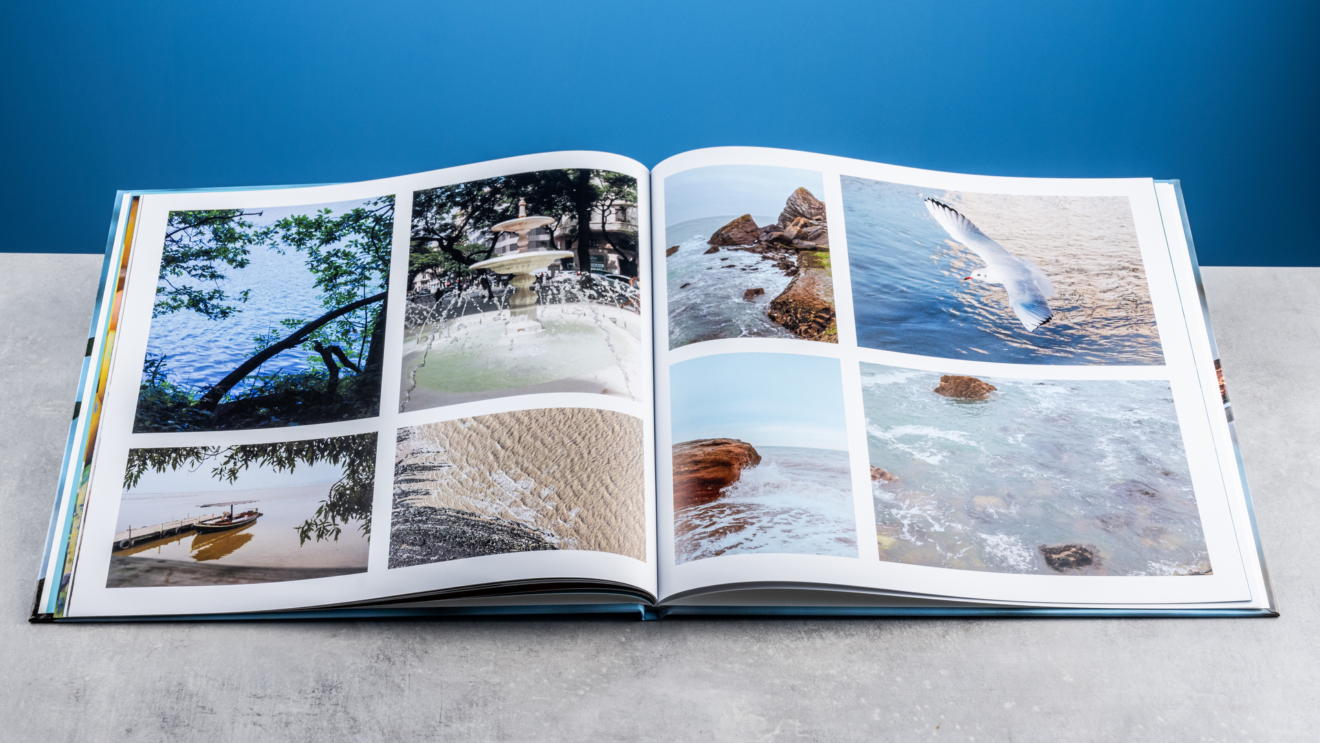 Σελίδες άλμπουμ φωτογραφιών Vistaprint φωτογραφημένες σε τραπέζι μπροστά σε μπλε φόντο