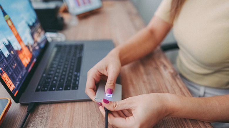 Ένα άτομο που συνδέει έναν εξωτερικό SSD σε φορητό υπολογιστή μέσω USB.