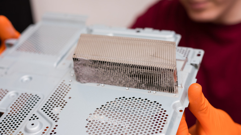 Χέρια που κρατούν σκονισμένο μέρος του PlayStation 4