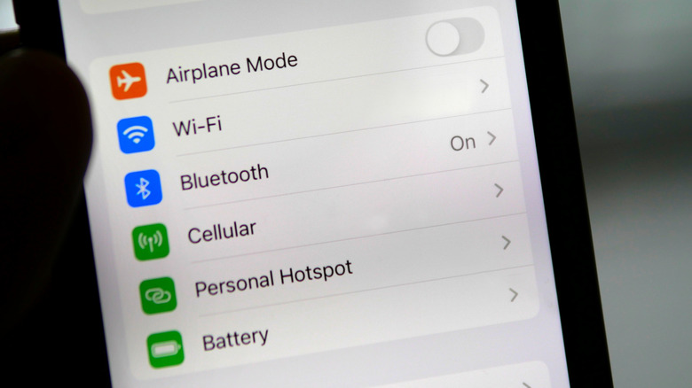 Ένα χέρι που κρατά ένα iPhone που εμφανίζει την οθόνη ρυθμίσεων που δείχνει ένα στοιχείο μενού για τη διαχείριση της μπαταρίας