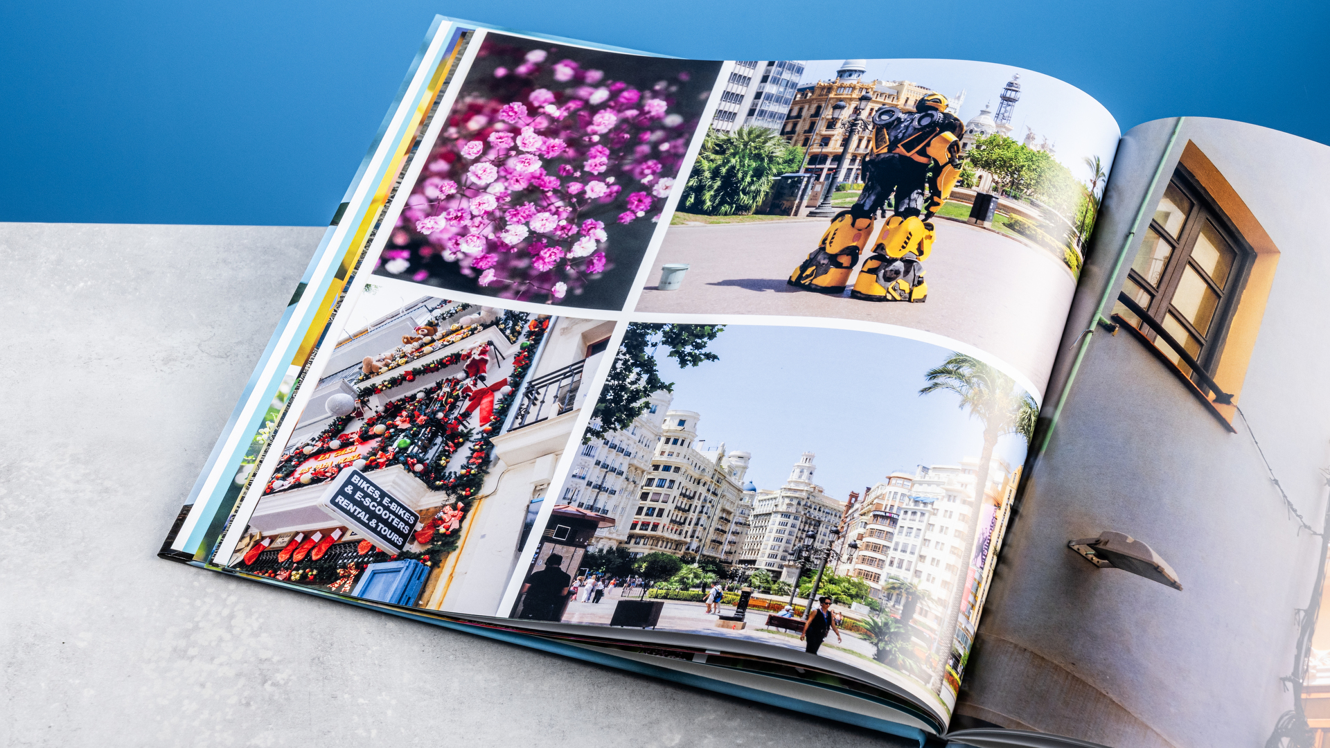 Σελίδες άλμπουμ φωτογραφιών Vistaprint φωτογραφημένες σε τραπέζι μπροστά σε μπλε φόντο