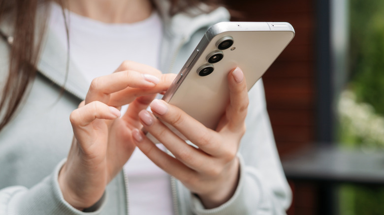 Μια γυναίκα που κρατά το smartphone Samsung Galaxy S25.