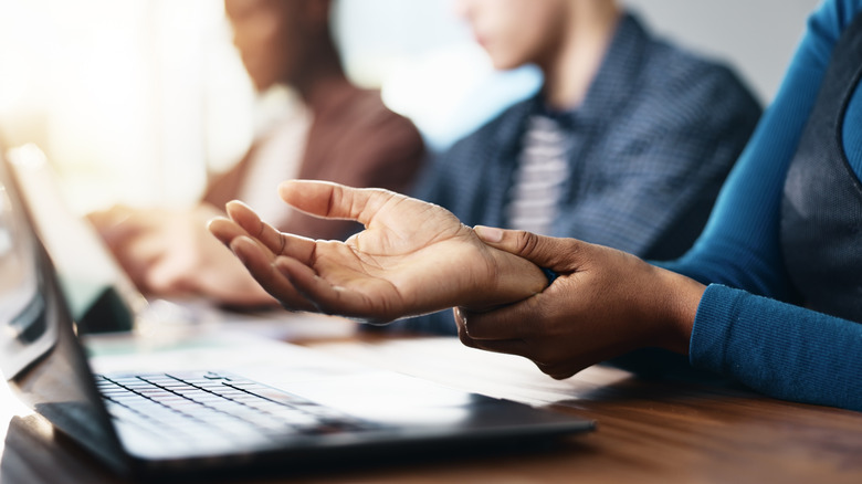 Άτομο στο φορητό υπολογιστή που κρατά τον καρπό λόγω πόνου από την πληκτρολόγηση