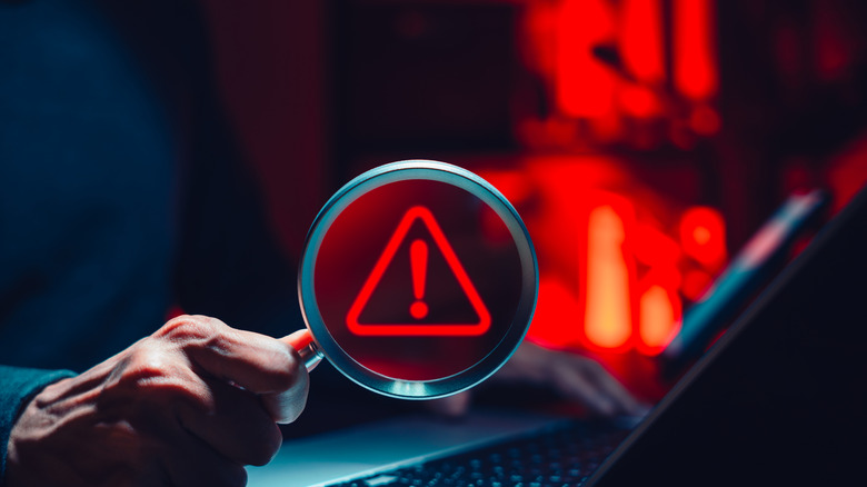 άνθρωπος που κρατά μεγεθυντικό φακό πάνω από φορητό υπολογιστή, έννοια της ανακάλυψης κακόβουλου λογισμικού