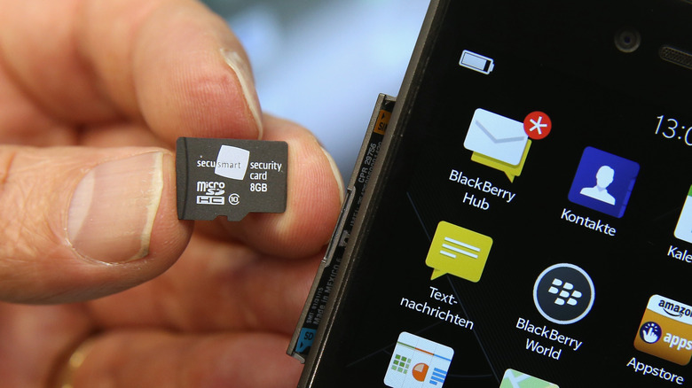 Άτομο που κρατά μια κάρτα microSD δίπλα σε ένα smartphone