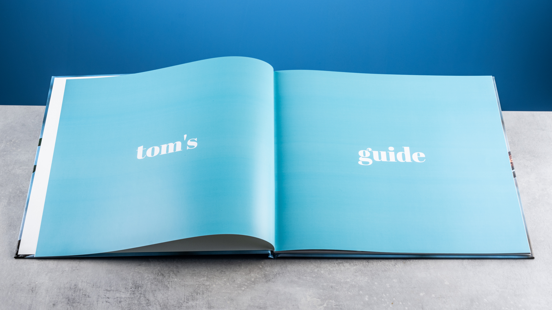 Σελίδες άλμπουμ φωτογραφιών Vistaprint φωτογραφημένες σε τραπέζι μπροστά σε μπλε φόντο